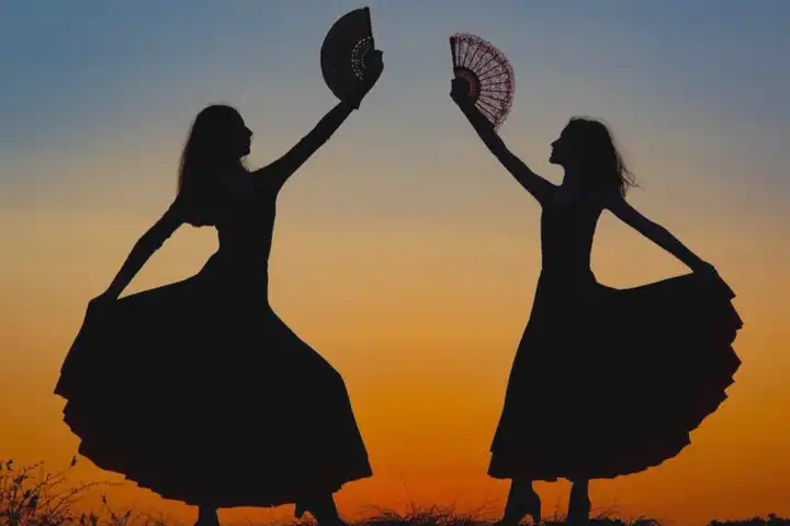 Feria de Abril te La Laguna - Silhouetten van twee flamenco dansers bij zonsondergang.